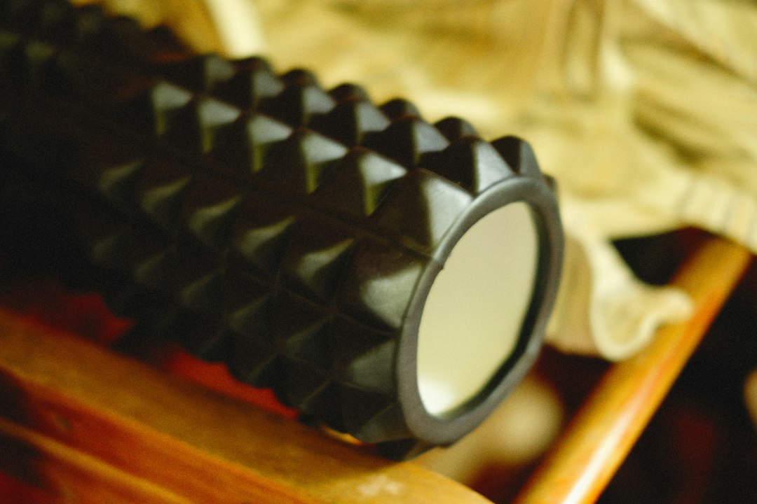 Detail of a black foam roller on a wooden surface